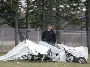 An FAA investigator Sunday, Nov. 3, 2013 examines the wreckage of a plane that crashed in Superior, Wis., Saturday after a midair collision with another plane. Both planes were carrying skydivers. No one was seriously injured in the incident. (AP Photo/The News-Tribune, Steve Kuchera)