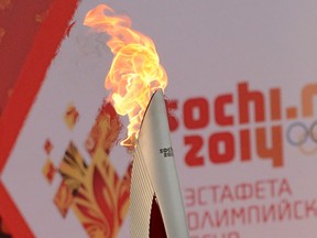 One of the Olympic torches rises in front of a poster with the Sochi 2014 Winter Olympic logo just outside the Red Square in Moscow, on October 7, 2013, during a ceremony to kick off the Sochi 2014 Winter Olympic torch relay across Russia (KIRILL KUDRYAVTSEV/AFP/Getty Images)