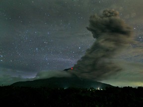 In this late Sunday, Nov. 24, 2013 photo, Mount Sinabung spews volcanic ash into the air as seen from Tiga Pancur, North Sumatra, Indonesia. Authorities raised the alert status for one of the country's most active volcanoes to the highest level Sunday after the mountain repeatedly sent hot clouds of gas down its slope following a series of eruptions in recent days. (AP Photo/Binsar Bakkara)