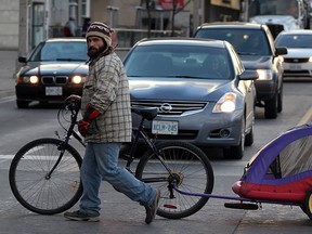 Cyclist Leslie Pilgrim uses Windsor's walks his bike across Riverside Drive at Ouellette Avenue, November 27, 2013. (NICK BRANCACCIO/The Windsor Star)