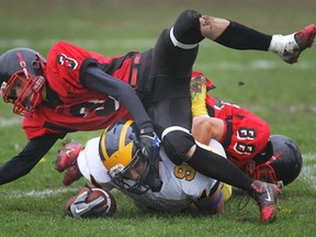 Kennedy's Ali Mehaidli, bottom, is tackled by Cole Lafferty, left, and Darren Sweetman of the Red Raiders during their playoff game at Windsor Stadium.  (DAN JANISSE/The Windsor Star)