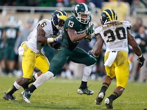 Michigan State's Bennie Fowler, centre, tries to avoid Michigan's Raymon Taylor, left, and Thomas Gordon at Spartan Stadium Saturday in East Lansing. (Photo by Gregory Shamus/Getty Images)