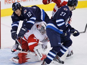 Winnipeg's Olli Jokinen, left, goes over the top of Detroit goaltender Jimmy Howard Monday  in Winnipeg. (THE CANADIAN PRESS/John Woods)