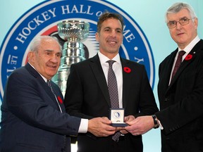Hockey Hall of Fame inductee Chris Chelios, centre, is presented with his ring by chairman Pat Quinn, right, and chair of the selection committee Jim Gregory at the Hall in Toronto. (THE CANADIAN PRESS/Frank Gunn)