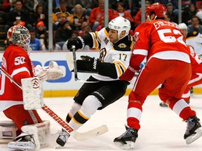 Red Wings goalie Jonas Gustavsson, left, stops a shot by Boston's Milan Lucic, centre, as Detroit's Jonathan Ericsson defends on the play in Detroit, Wednesday, Nov. 27, 2013. (AP Photo/Paul Sancya)