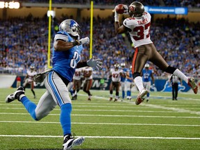 Tampa Bay free safety Keith Tandy, right, intercepts a pass intended for Detroit wide receiver Calvin Johnson in Detroit, Sunday, Nov. 24, 2013. (AP Photo/Rick Osentoski)