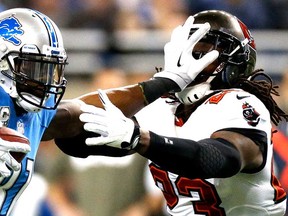 Detroit's Calvin Johnson, left, stiff arms Tampa Bay's Mark Barron #23 at Ford Field on November 24, 2013 in Detroit. (Gregory Shamus/Getty Images)