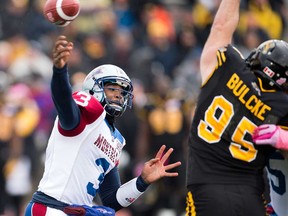 Montreal QB Troy Smith, left, makes a pass under pressure from Hamilton Tiger-Cats defensive lineman Brian Bulcke during CFL action in Guelph October 26, 2013. (THE CANADIAN PRESS/Frank Gunn)