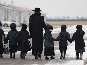 In this file photo, a young man leads a group of children from the Lev Tahor, a fundamentalist Jewish group, to their current home in Chatham, Ontario on November 28, 2013. (JASON KRYK/The Windsor Star)