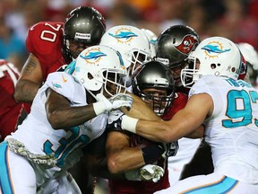 Tampa Bay's Brian Leonard, centre, is tackled by  Miami's Chris Clemons, left, and  Jason Trusnik November 11, 2013 in Tampa, Florida.  (Mike Ehrmann/Getty Images)