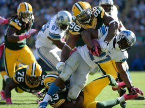 Detroit's Reggie Bush, right, is hit for a loss by Mike Neal, top, at Lambeau Field on October 6, 2013 in Green Bay, The Lions host the Packers Thursday (12:30 p.m., Fox), (Harry How/Getty Images)