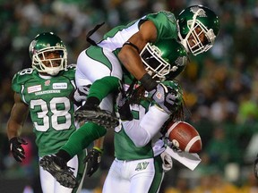 Saskatchewan's Weldon Brown, centre, celebrates with teammates Dwight Anderson, right, following an interception against the Hamilton Tiger-Cats during the Grey Cup on November 24, 2013 in Regina. The gold-wrapped TV deal the CFL secured last year will make financial life a lot easier for every franchise this season.But for a few weeks this spring, it also played a significant role in a labour dispute that could have stopped the season from getting off the ground. (Liam Richards/The Canadian Press)