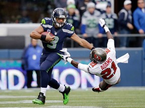 Seattle quarterback Russell Wilson, left, pushes off of Tampa Bay's Michael Adams on a long run to set up a touchdown Sunday, Nov. 3, 2013, in Seattle. (AP Photo/Elaine Thompson)