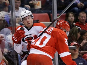 Detroit's Drew Miller, right, checks Carolina defenseman Brett Bellemore of Windsor during the second period of an NHL hockey game in Detroit, Thursday, Nov. 21, 2013. (AP Photo/Carlos Osorio)