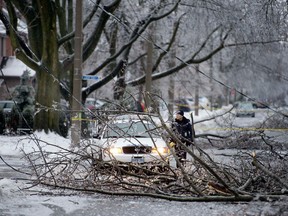 A police officer cordons off a downed power line and tree branches in the Leaside area as freezing rain has left many parts of Toronto without power for possibly up to 72 hours, Sunday Dec. 22, 2013.  [Peter Thompson/National Post]