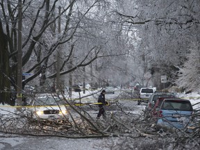 A police officer cordons off a downed power line and tree branches in the Leaside area as freezing rain left many parts of Toronto without power for possibly up to 72 hours, Sunday Dec. 22, 2013.  [Peter J. Thompson/National Post]