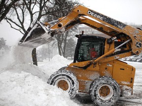 A small excavator is used to remove snow in a parking lot on Ouellette Avenue after an overnight snowstorm, Saturday, Dec. 14, 2013. (DAX MELMER/The Windsor Star)