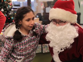 Owen Gillis-Bezaire, right, dressed as Santa Claus, is greeting by Windsor Regional Hospital patient Serena Mejacci on Dec. 23, 2013 at Windsor Regional Hospital.  Gillis-Bezaire handed out gifts to children at the hospital. (JASON KRYK/The Windsor Star)