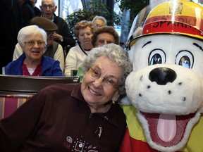 Lorraine Koski, 91, poses with Sparky of Windsor Fire Services as firefighters collect an "unbelievable amount" of new, unwrapped toys from residents and staff at Chartwell Oak Park Terrace on North Service Road, Tuesday December 10, 2013.  Donated toys are earmarked for needy families during the holidays. (NICK BRANCACCIO/The Windsor Star)