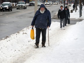 Ray Poisson slowly navigates a snow-covered sidewalk on Ouellette Avenue at Elliott Street Tuesday December 17, 2013.  (NICK BRANCACCIO/The Windsor Star)