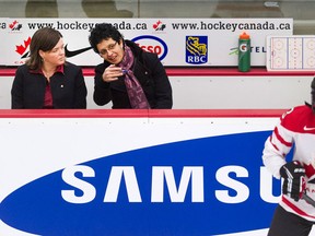 Canada's coaches Danielle Goyette, centre, and Lisa Haley watch from the bench as Jocelyn Larocque, right, warms up before playing the USA in Calgary. (THE CANADIAN PRESS/Larry MacDougal)