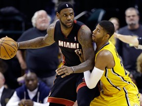 Miami's LeBron James, left, is defended by Indiana's Paul George.  (AP Photo/Michael Conroy)