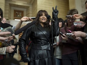 Terri-Jean Bedford flashes a victory sign as she speaks with the media after learning Canada's highest court struck down the country's prostitution laws at the Supreme Court of Canada in Ottawa Friday December 20, 2013. THE CANADIAN PRESS/Adrian Wyld