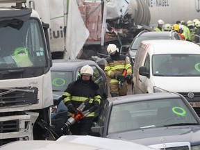 Medics carry equipment to a crash scene on the A19 highway in Zonnebeke, western Belgium, Tuesday, Dec.3, 2013. Dozens of cars and trucks crashed in dense morning fog, killing at least one and injuring dozens more. (AP Photo/Yves Logghe)