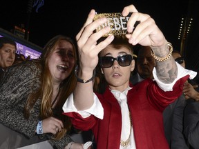 In this Dec. 18, 2013 file photo, singer Justin Bieber takes a "selfie" with a fan at the premiere of the feature film "Justin Bieber's Believe" at Regal Cinemas L.A. Live in Los Angeles. The word selfie is on a list of among those words selected for elimination in Michigan's Lake Superior State University's 39th annual batch of words to banish due to overuse, overreliance and overall fatigue. Others include "twerking," "Mr. Mom" and "on steroids." (AP Photo/Dan Steinberg, Invision)