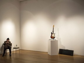 George Wein, founder of the Newport Folk and Jazz Festivals, sits next to the Fender Stratocaster electric guitar played by musician Bob Dylan on July 25, 1965 at Newport Folk Festival, better known as "the night Dyan went electric" at an auction preview at Christie's on November 25, 2013 in New York City. The guitar is estimated at $300,000 to $500,000. (Photo by Andrew Burton/Getty Images)