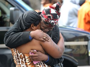 The same guns that spill tears and blood on the streets of Detroit are smuggled into Windsor by drug mules, usually educated females, hand-selected by kingpins for their unassuming manner and crime-free background. In this photo, two women console each other after a double fatal shooting in Detroit on Friday, Sept. 13, 2013. (Dan Janisse/The Windsor Star)