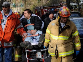 In this file photo taken on Sunday, Dec. 1, 2013, Metro North Railroad engineer William Rockefeller is wheeled on a stretcher away from the area where the commuter train he was operating derailed in the Bronx borough of New York. The engineer driving the commuter train that went off the rails in New York City last weekend has been suspended without pay according to a spokesman for Metro-North Railroad Thursday Dec. 5, 2013. (AP Photo/Robert Stolarik, File)