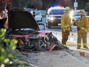 First responders gather evidence near the wreckage of a Porsche sports car that crashed into a light pole on Hercules Street near Kelly Johnson Parkway in Valencia on Saturday, Nov. 30, 2013. A publicist for actor Paul Walker says the star of the "Fast & Furious" movie series has died in a car crash north of Los Angeles. He was 40. Ame Van Iden says Walker died Saturday afternoon. No further details were released. (AP Photo/The Santa Clarita Valley Signal, Dan Watson)