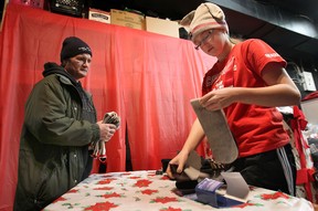 Sarah Lewis, 13, hands out some socks to a client of the Street Help/Unit 7 Homeless Services organization, Wed. Dec. 18, 2013, in Windsor, Ont. She also presented a cheque for $11,669 and over 5000 pairs of socks in total. (DAN JANISSE/The Windsor Star)