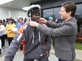 Mucci Farms in Kingsville, Ont. handed out helmets, safety reflectors and lights to hundreds of their migrant workers Thursday, Nov. 21, 2013. The Ride Safe project encourages workers who travel by bike to do it in a safe manner. Danny Mucci, right, general manager of the business give Vaughn Pusey a hand with his new helmet. (DAN JANISSE/The Windsor Star)