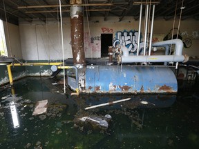 Water fills the boiler room at the former Frederick Douglass Academy in Detroit Tuesday, Oct. 29, 2013. How much treated water is lost this way in Detroit is anybody’s guess. Not even the city knows. But the cost is passed on in higher rates to water customers in the city, which in July became the largest in U.S. history to file for bankruptcy, and ironically shut off many of its decorative fountains last summer as a cost-saving measure. (AP Photo/Paul Sancya)