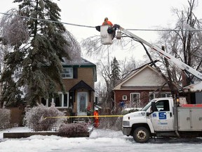 Workers repair downed power lines  in Scarborough, Monday, Dec. 23, 2013, after a severe ice storm hit Toronto. Roughly 23,000 customers in Ontario — 18,000 of them in Toronto — are still waiting for the lights and heat to be restored, seven days after the power went out. Just over 6,800 customers in Quebec and about 12,000 in New Brunswick are in the same cold, dark, boat as of mid-morning Saturday. (THE CANADIAN PRESS/Galit Rodan)