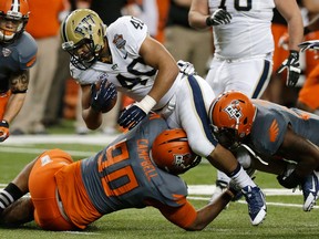 Pittsburgh's James Conner, centre, is tackled by Bowling Green's Jairus Campbell, left, during the first half of the Little Caesars Pizza Bowl in Detroit, (AP Photo/Duane Burleson)