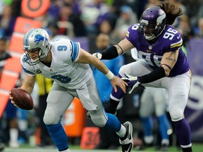 Detroit's Matthew Stafford, left, avoids a sack by Minnesota's Brian Robison at the Hubert H. Humphrey Metrodome in Minneapolis. (Photo by Hannah Foslien/Getty Images)
