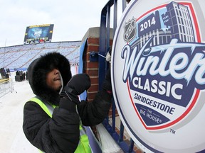 A worker puts up a Winter Classic sign at Michigan Stadium Monday. (Getty Images)