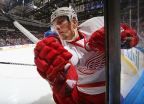 Detroit's Justin Abdelkader is checked into the glass against the New York Islanders at Nassau Veterans Memorial Coliseum. (Photo by Al Bello/Getty Images)