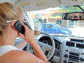 A typical distracted driver; talking on a  cellphone while drinking a coffee behind the wheel. (Postmedia News files)