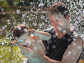 Keith Hennin and his son Noah, age 2, stay cool while playing in the Mic Mac Park splash pad Monday July 15, 2013 in Windsor, Ontario. Extreme heat has hit southwestern Ontario and will continue for the week. (JASON KRYK/The Windsor Star)