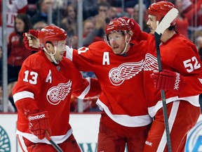 Detroit Daniel Alfredsson, centre, celebrates his assist with teammates Pavel Datsyuk, left, and Jonathan Ericsson on a goal by Joakim Andersson against the Calgary Flames, Thursday, Dec. 19, 2013, in Detroit. (AP Photo/Duane Burleson)