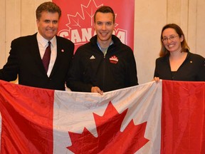 Canadian chef de mission Gord Grace, left, flag bearer Brendan Bottcher and Jessica Blitt, counsellor of public affairs and advocacy for the Embassy of Canada in Italy, pose with the Canadian flag Monday, December 9 2013 in Trento Italy. (Canadian Interuniversity Sport photo)