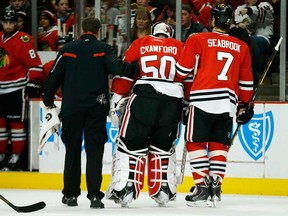 Blackhawks goalie Corey Crawford, centre, is helped off the ice after suffering an injury against the Florida Panthers during the first period on Sunday, Dec. 8, 2013, in Chicago, Ill. (AP Photo/Andrew A. Nelles)