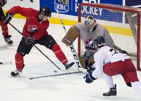 Tecumseh's Kerby Rychel, left, deflects a shot against CIS Toronto Selects goalie Garrett Sheehan, centre, as defenceman Lane Werbowski looks on during an exhibition game at the world juniors selection camp in Toronto on Saturday, Dec. 14, 2013. Rychel had two assists in Canada's 3-0 win. (THE CANADIAN PRESS/Nathan Denette)