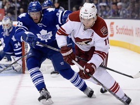 Toronto's Carl Gunnarsson, left, battles Phoenix's Martin Hanzal, during first period NHL action in Toronto on Thursday, December 19, 2013. (THE CANADIAN PRESS/Frank Gunn)