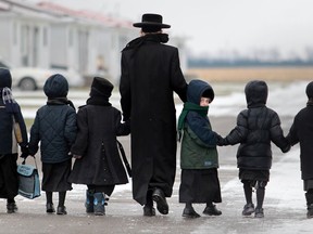 A youth leads a group of children from the Lev Tahor, a fundamentalist Jewish group, to their current home in Chatham, Ontario on November 28, 2013. (JASON KRYK/The Windsor Star)