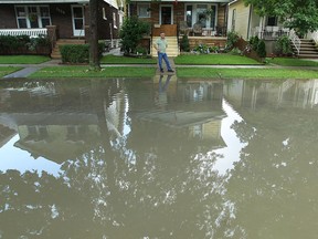A Windermere Road homeowner looks out over a flooded street in this july 2013 file photo. (Tyler Brownbridge / The Windsor Star)